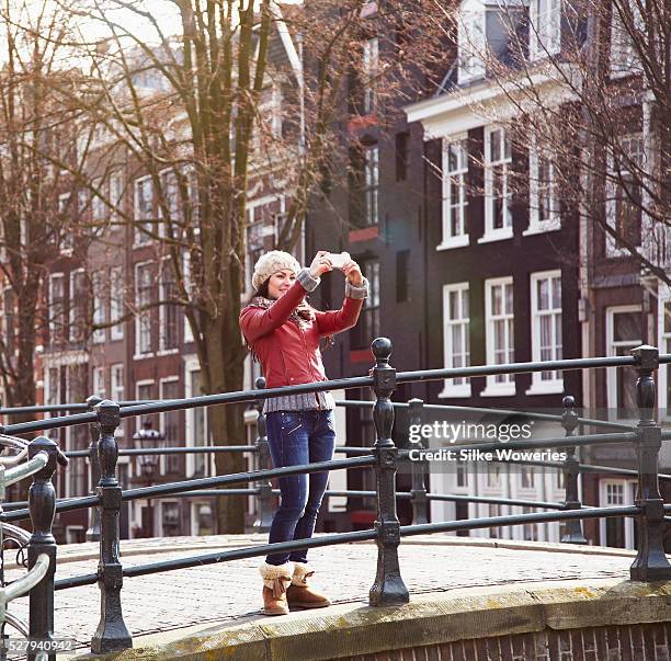 woman taking picture with mobile phone - amsterdam winter stock pictures, royalty-free photos & images