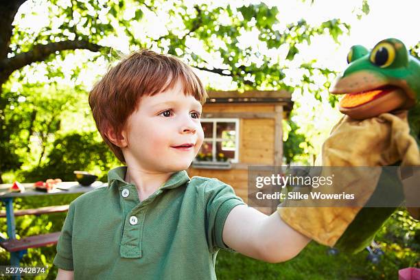 portrait of red haired boy (4-5) playing with puppet in garden - puppeteer photos et images de collection