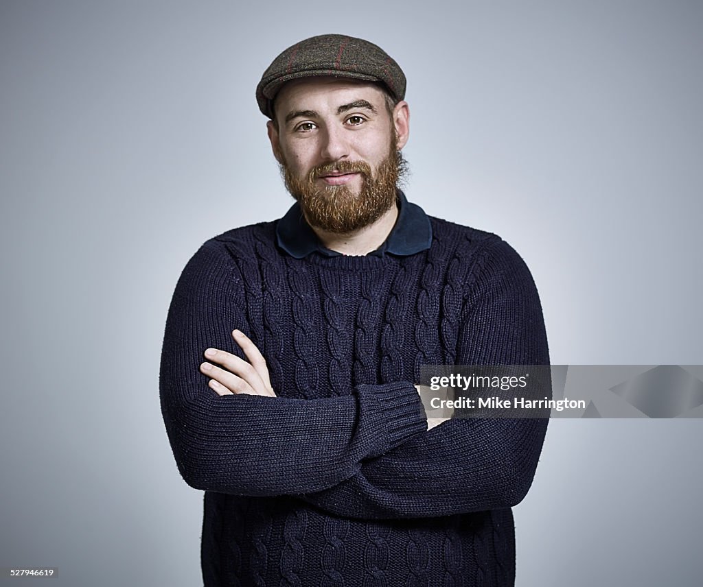 Bearded young man wearing cap and woolly jumper.