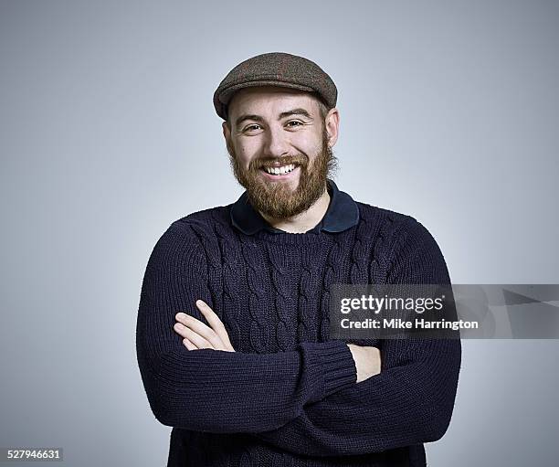 bearded man wearing jumper and flat cap smiling - flat cap 個照片及圖片檔