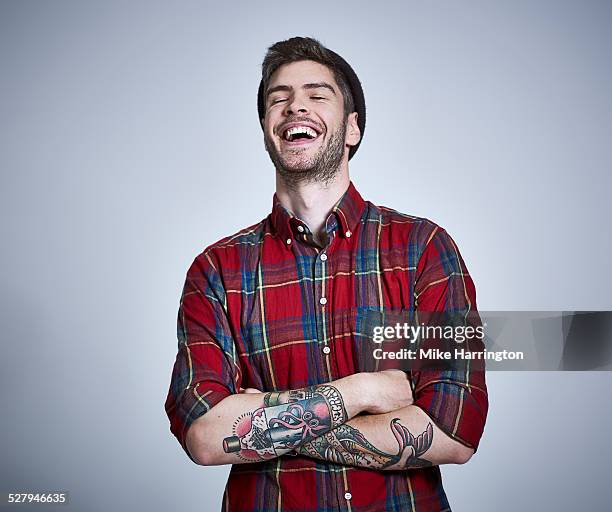 tattooed young male in check shirt laughing. - man laughing photos et images de collection