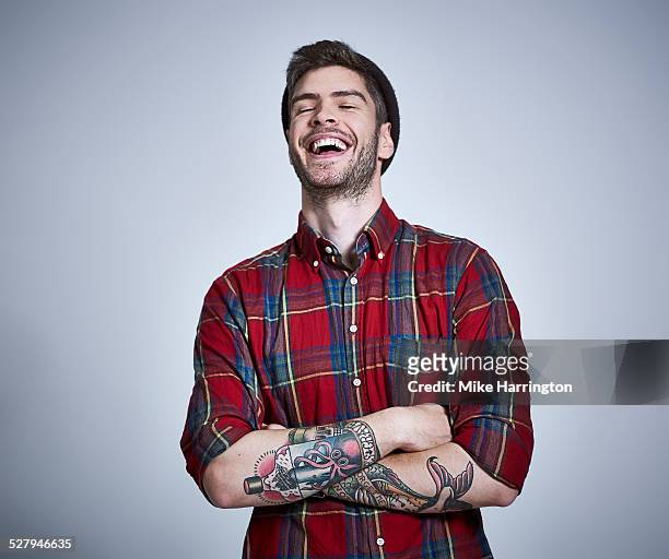 tattooed young male in check shirt laughing. - cool attitude foto e immagini stock