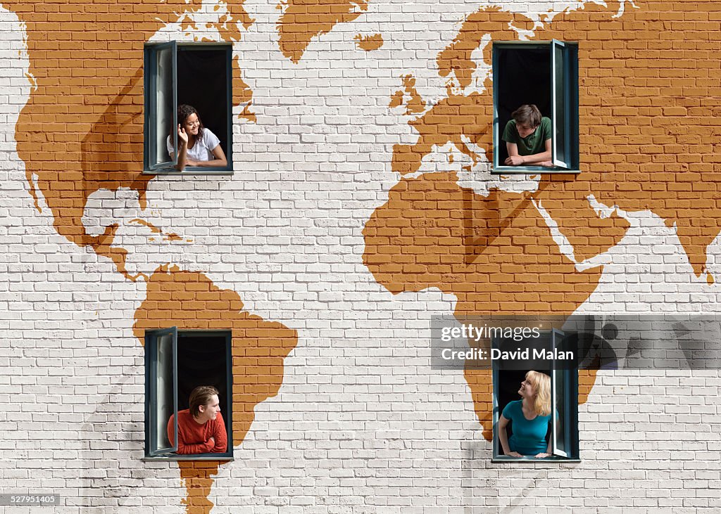 People in windows in a wall with painted map