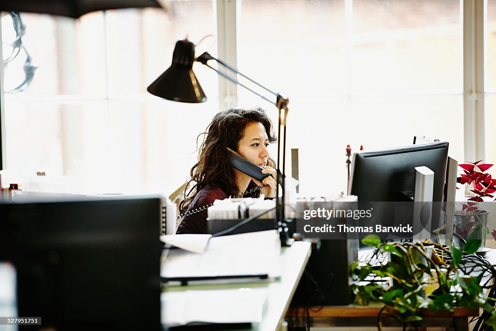 Businesswoman sitting in office on phone
