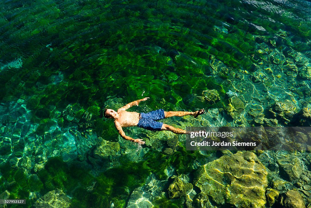 A man floating in clear lake water.