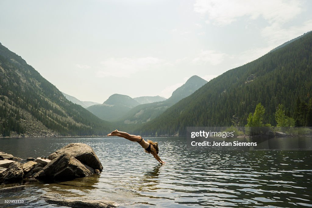 A woman diving off a rock.