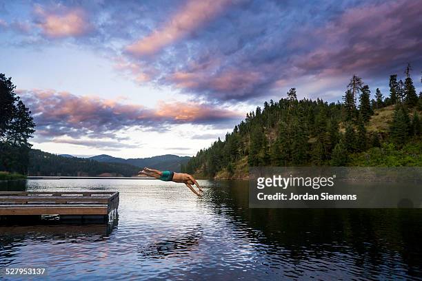 a man diving into a lake. - montana moody sky stock pictures, royalty-free photos & images
