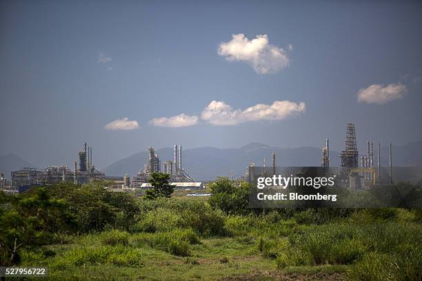 Petrobras's Comperj oil refinery stands behind a farm in Itaborai, Brazil, on Tuesday, April 12, 2016. Just 30 miles east of the bustling Copacabana...