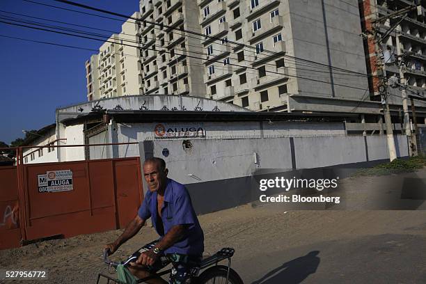 Man rides a bicycle past unfinished buildings in Itaborai, Brazil, on Tuesday, April 12, 2016. Just 30 miles east of the bustling Copacabana beach,...