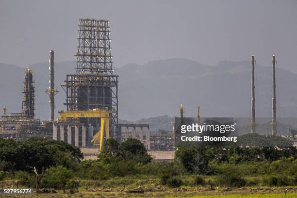Petrobras's Comperj oil refinery stands behind a farm in Itaborai, Brazil, on Tuesday, April 12, 2016. Just 30 miles east of the bustling Copacabana...