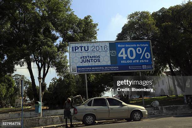 Man opens the trunk of his car while parked in front of signs advertising a 40 percent discount for early real estate taxpayers in Itaborai, Brazil,...