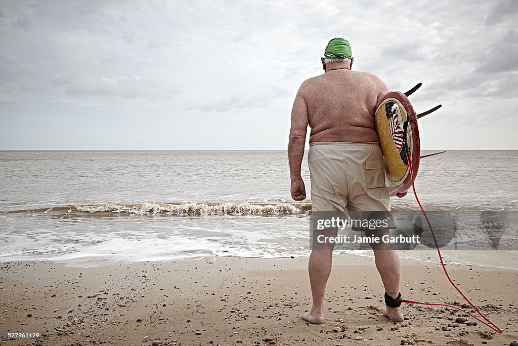 Elderly overweight surfer with back to camera