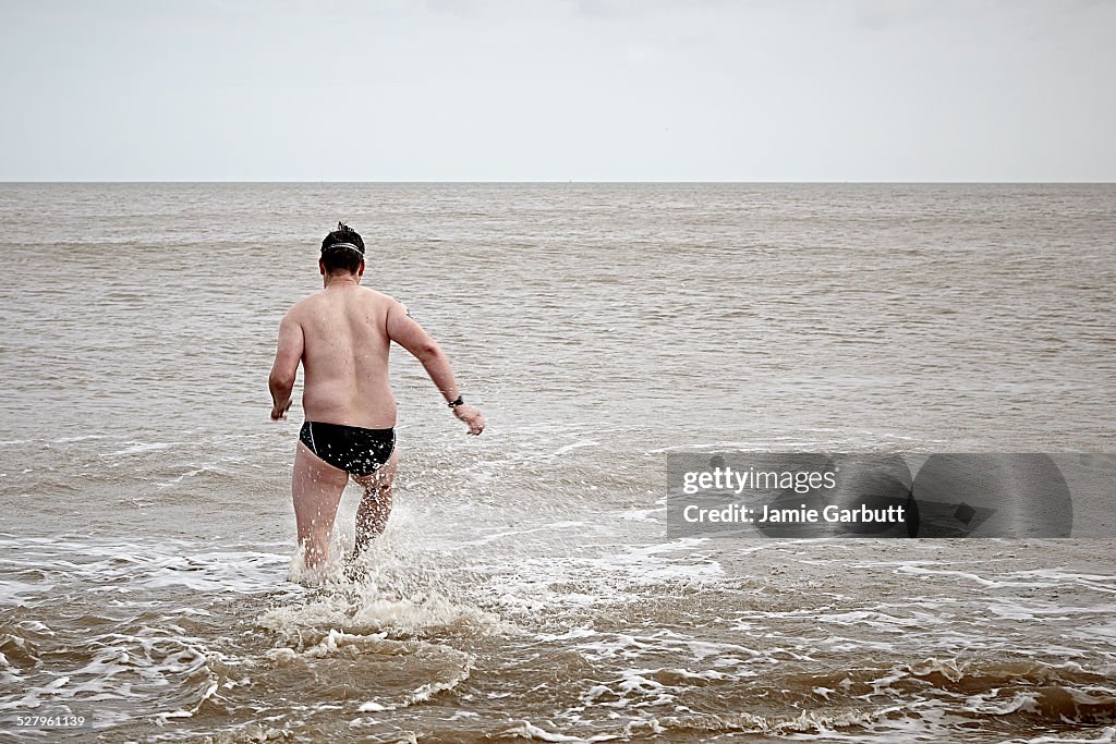 A overweight swimmer running into the sea