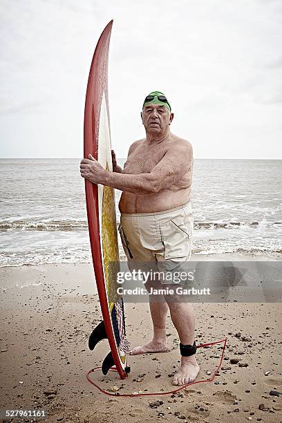 elderly male surfer holding his surf board - fat guy on beach fotografías e imágenes de stock