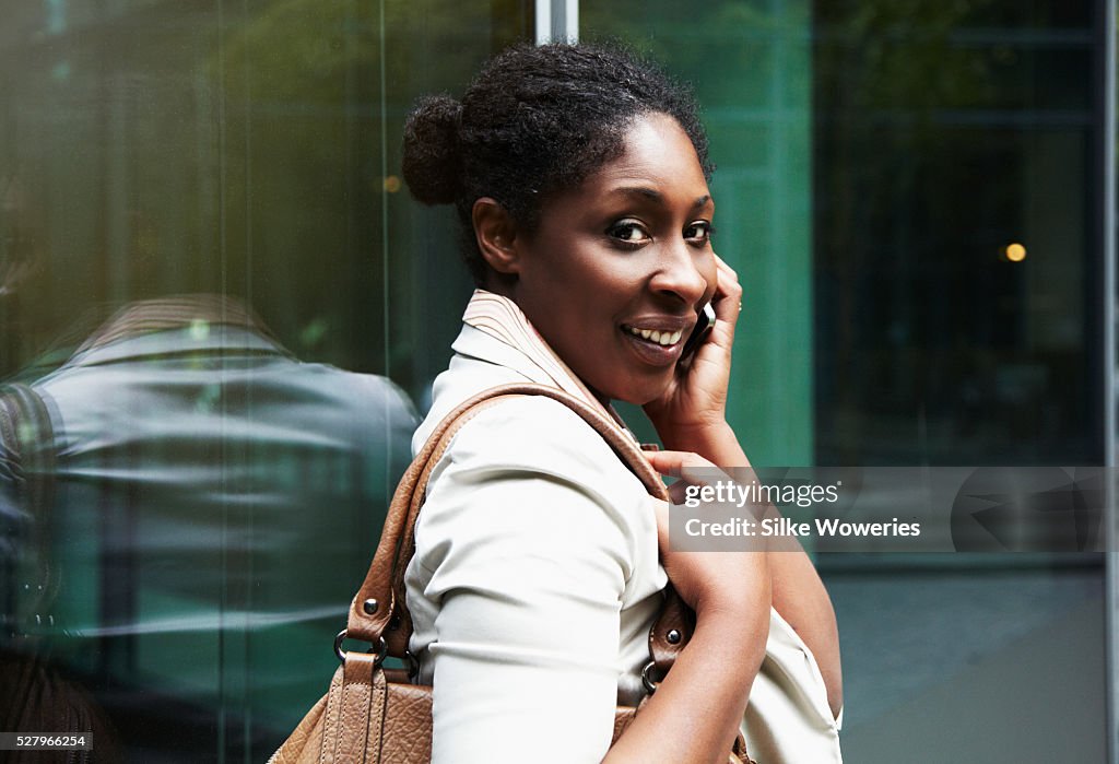 Portrait of a content afro-american businesswoman taking on her smartphone