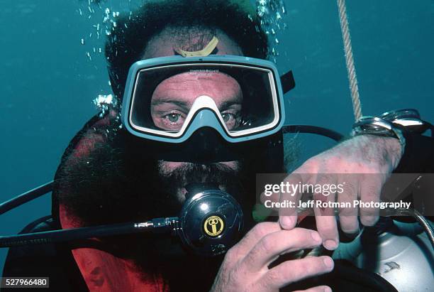 Scuba diver holds on to equipment and breathes through a regulator as he decompresses before rising to the surface of the Red Sea.