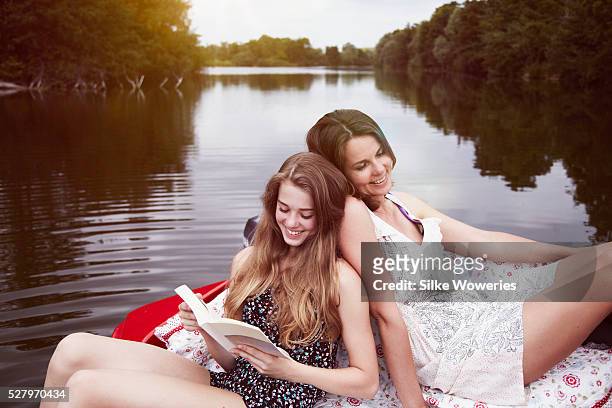 portrait of a mother and her teenage daughter relaxing in a red boat - girl with mother stock-fotos und bilder