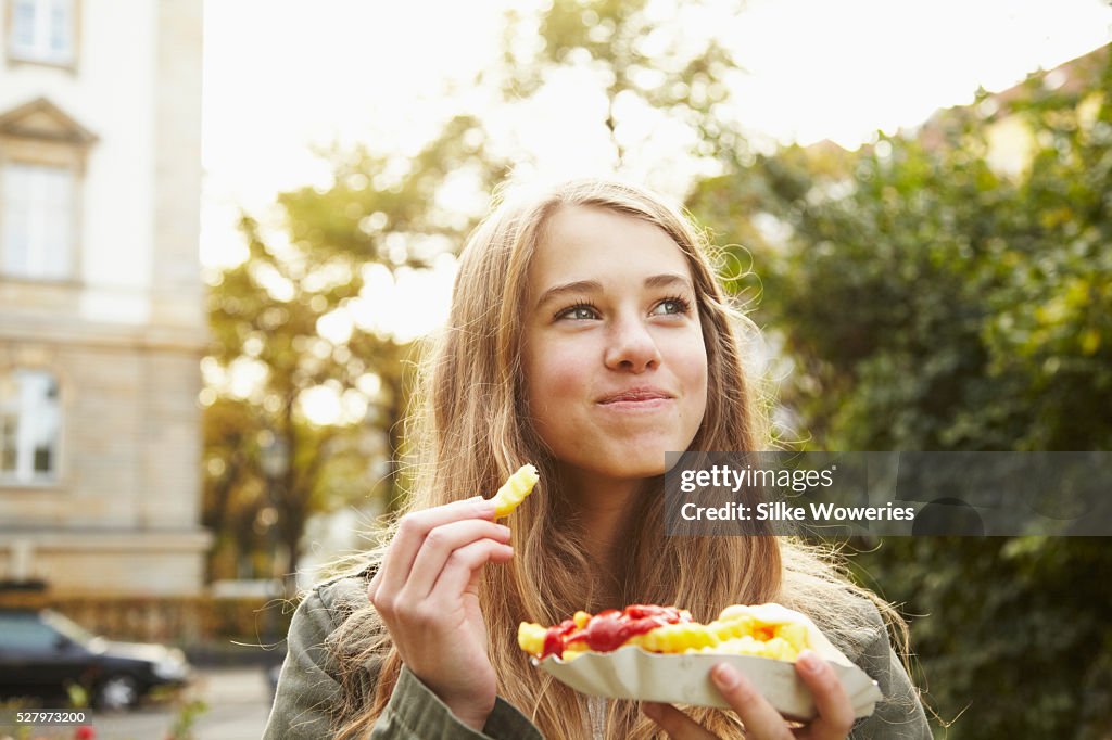 Portrait of a teenage girl eating french fries