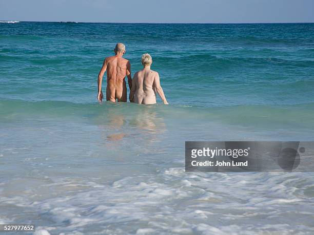 senior couple wading nude in ocean - man skinny dipping stock pictures, royalty-free photos & images