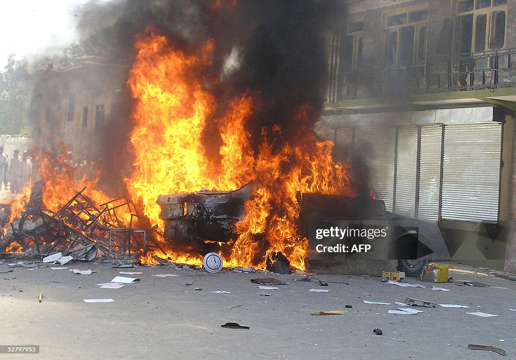 A car burns in the street as Afghan stud