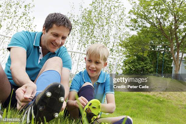 father and son putting on their football shoes. - football boot stock pictures, royalty-free photos & images