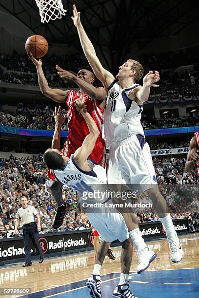 Dirk Nowitzki and Devin Harris of the Dallas Mavericks try to block a layup by Tracy McGrady of the Houston Rockets in Game five of the Western...
