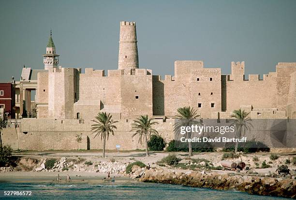 The Ribat of Harthema, a fortress, stands on the waterfront of Monastir. A minaret of a neighboring mosque peeks over the end. Tunisia. | Location:...