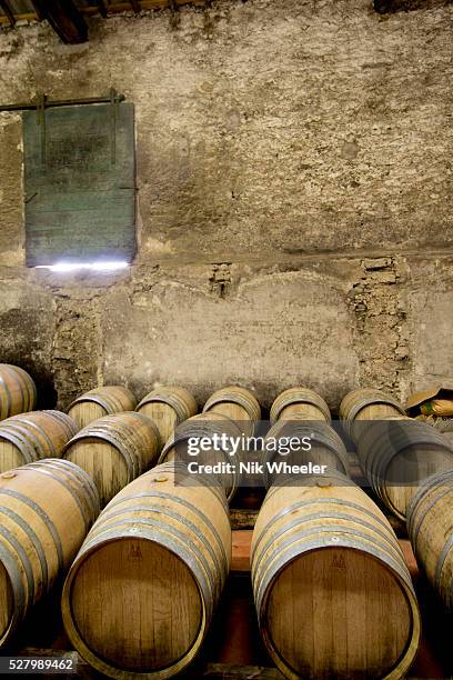 Wine barrels are stacked against a wall in the winery cellars of Domaine Peyrat, an historic winery set among vineyards near Pezenas in the Languedoc...