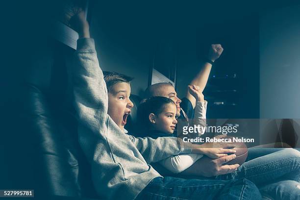 father, son and daughter watching football game - family game night stock-fotos und bilder