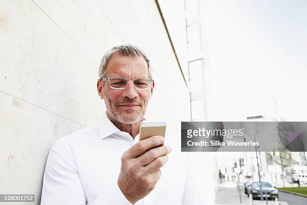 middle-aged businessman texting in financial district - 50 59 years stock pictures, royalty-free photos & images