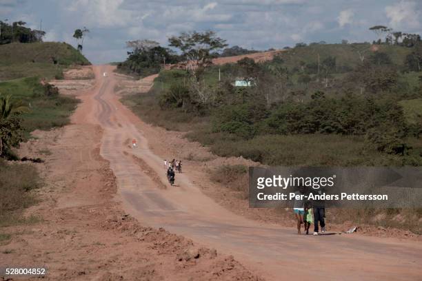 Villagers walk on a newly constructed road in the Amazon rainforest in Acre State, Brazil