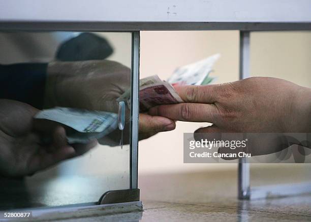 Passenger buys subway tickets with Chinese yuan banknotes at a ticket office on May 12, 2005 in Beijing, China. China's central bank said it will not...
