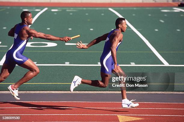 relay racers handing-off baton - stafett bildbanksfoton och bilder