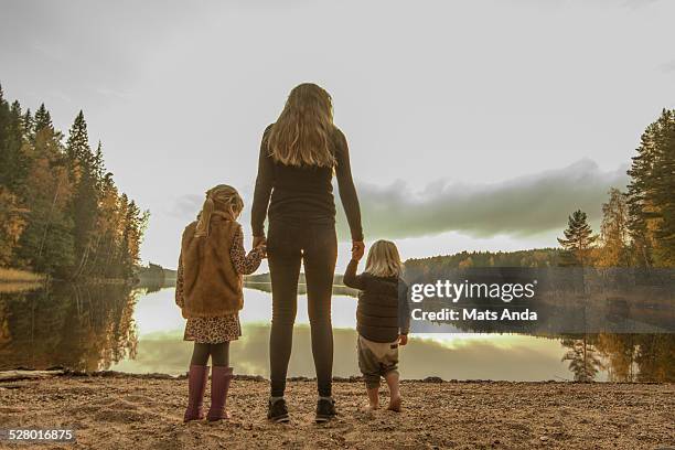 mother and two kids on a lake beach in fall - sad mum stock pictures, royalty-free photos & images