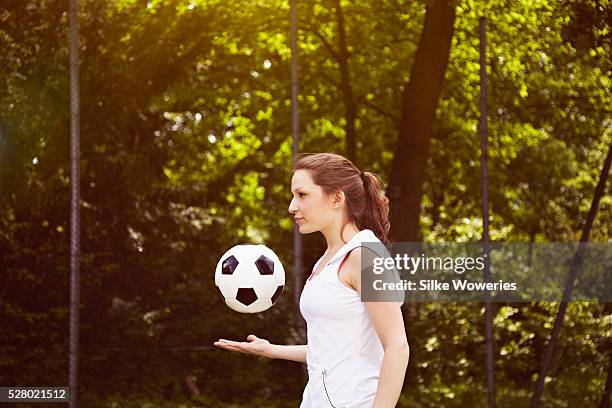 portrait of young adult woman throwing soccer ball into air - sleeveless ストックフォトと画像