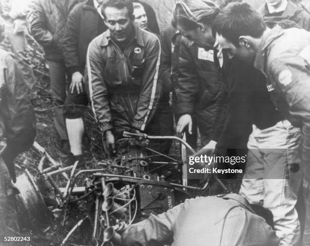 British racing driver Graham Hill is among those viewing the wreckage of the car driven by British racing driver Jim Clark at the time of his fatal...