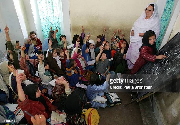 Young female Afghans raise their hands to take a turn at the bulletin board during a Dari language class at the Aschiana school for street children...