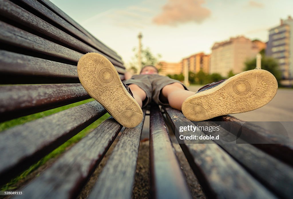 Sole shoes closeup of boy lying on a wooden bench