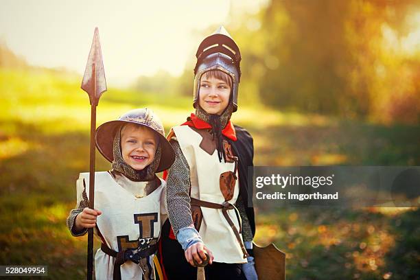 kids dressed up as knights playing outdoors - middeleeuws stockfoto's en -beelden