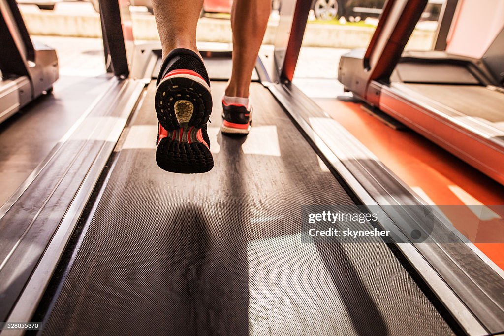 Feet of a runner on treadmill in a gym.