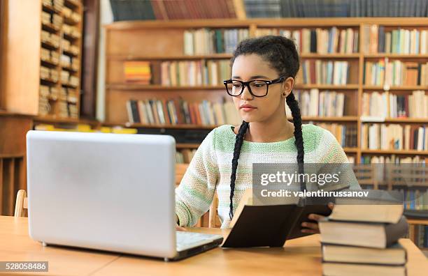 concentrated young woman using a laptop in the library - test preparation stock pictures, royalty-free photos & images