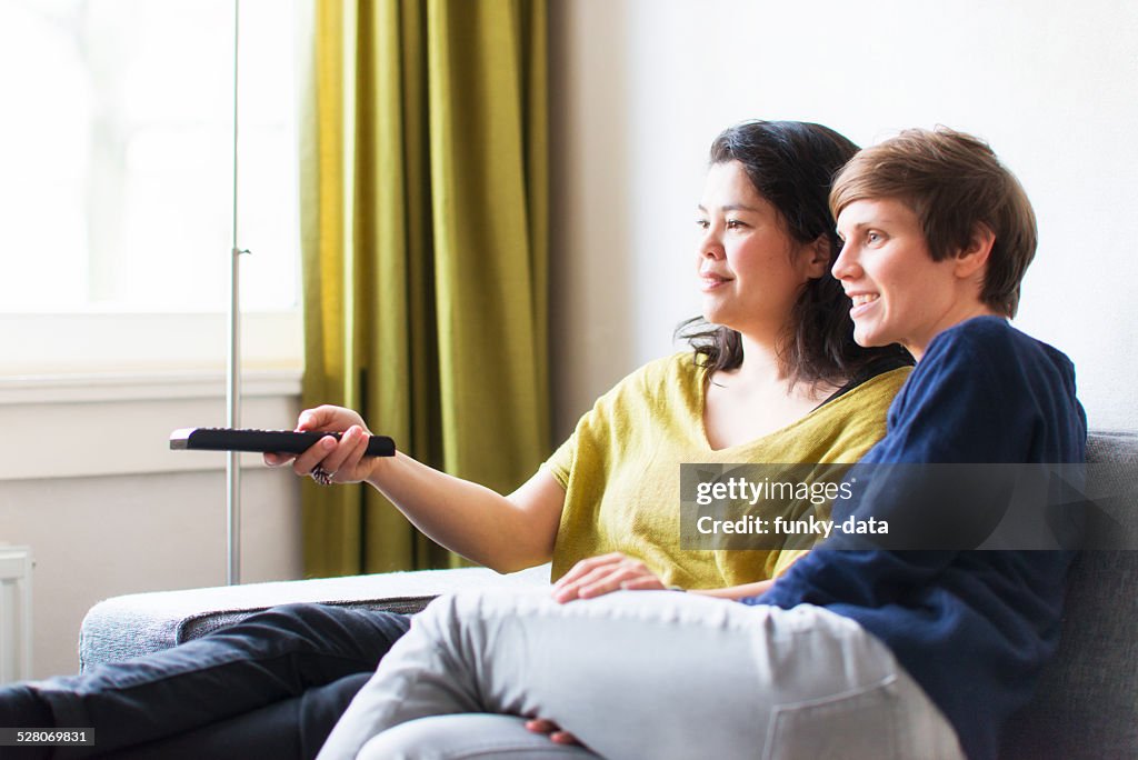 Real life lesbian couple is watching TV at home