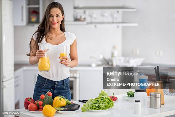 woman in the kitchen holding orange juice - extreme dieting stock pictures, royalty-free photos & images