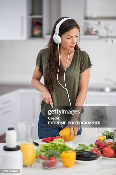 woman with headphones cutting bell pepper - mp3 juices stock pictures, royalty-free photos & images