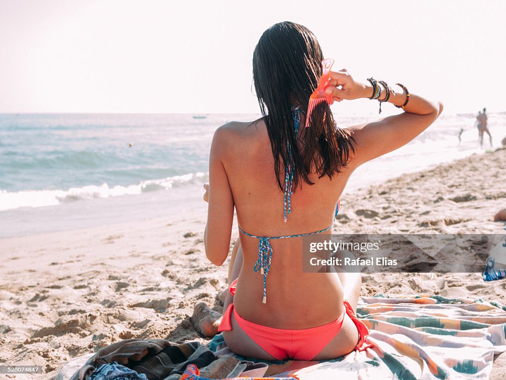 Atractive woman combing her hair on the beach