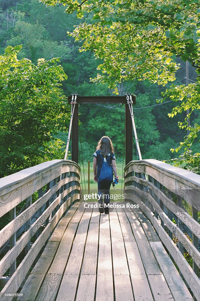 Girl walking away over a wooden bridge