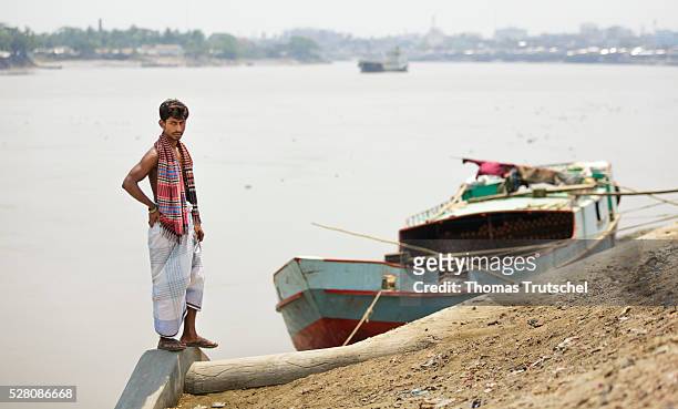 Man stands in front of a transport ship at the harbour of Khulna on April 11, 2016 in Khulna, Bangladesh.