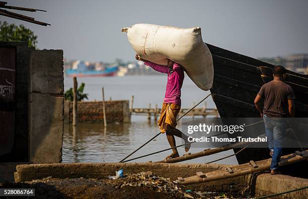 Man transports bags with his head on board of a cargo ship on April 11, 2016 in Khulna, Bangladesh.