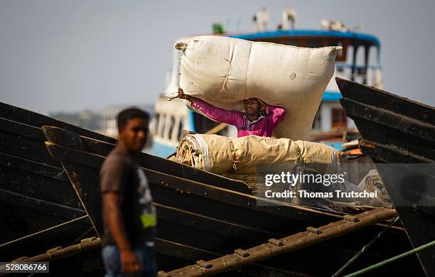 Man transports bags with his head on board of a cargo ship on April 11, 2016 in Khulna, Bangladesh.