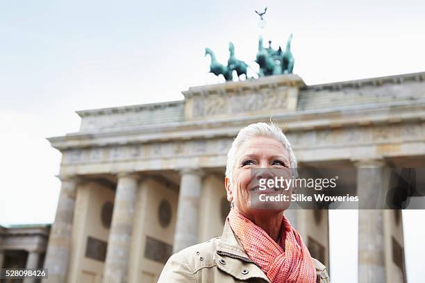 portrait of a happy and content senior woman in front of the brandenburger tor, berlin. - brandenburg gate berlin stockfoto's en -beelden